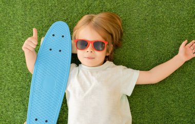 Tatlı çocuk, sarışın çocuk, dışarıda kaykayla oynuyor..