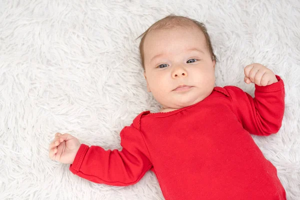 漂亮的女婴躺在床上 看着穿着红衫的相机 — 图库照片