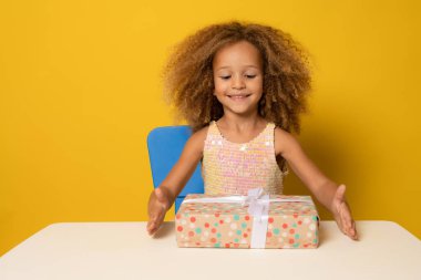Güzel hediyeyle tatmin olmuş bir kız çocuğu. Küçük sevimli kızın portresi hediye kutusunu açıyor ve kameraya gülümsüyor, doğum gününü kutluyor..