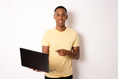 Genç ve modern iş adamının portresi dizüstü bilgisayarını tutuyor ve mutlu bir gülümsemeyle kameraya bakıyor.