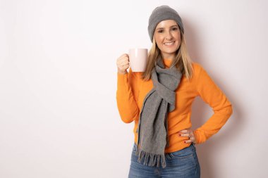 Turuncu süveterli ve elinde beyaz arka planda izole edilmiş bir fincan kahve tutan mutlu genç kadın..