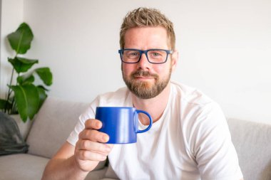Young caucasian man smiling confident drinking coffee at home