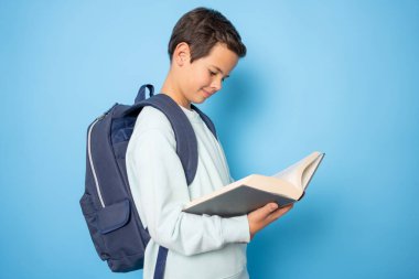 Mavi arka planda kitap okuyan ve gülümseyen genç bir çocuk görüntüsü