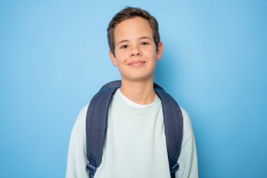 Mavi arka planda izole edilmiş mutlu bir öğrencinin portresi.