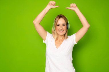 Young fitness woman runner with headphone, isolated on green background. Dynamic movement.