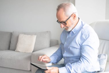 Komuta sizde dijital tablet haber okuma gülümseyerek. Evde, taşınabilir bilgisayarla neşeli heyecan olgun erkek kopya alanı