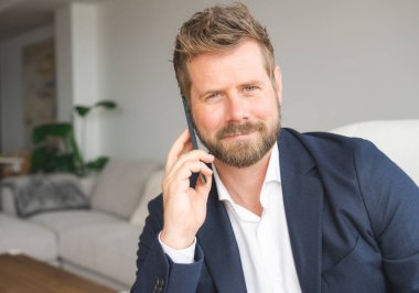 Portrait of Smiling Businessman using smartphone while sitting on sofa at his home.young people working on mobile devices, business technology lifestyle concept