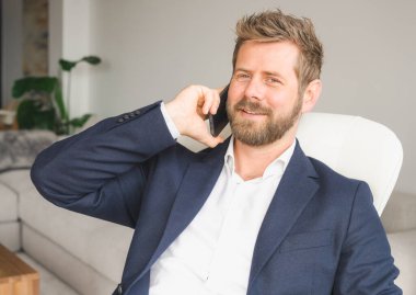 Portrait of Smiling Businessman using smartphone while sitting on sofa at his home.young people working on mobile devices, business technology lifestyle concept