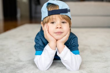 Shot of an adorable caucasian little boy lying down on a carpet and watching tv or play game at home
