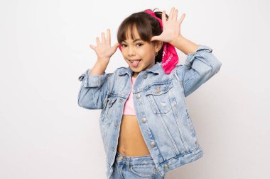 Portrait of a happy funny laughing child girl in denim clothing standing isolated over white background.
