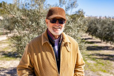 Elderly man smiling outdoors in nature looking to camera.