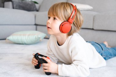 Evde otururken oyun konsolu kullanan küçük çocuk gerçek insanların gerçek eğlence konseptini kullanıyor.