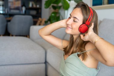 Rahat giyimli güzel bir kadının yan görünüm portresi evde müzik dinlemenin keyfini çıkarıyor.
