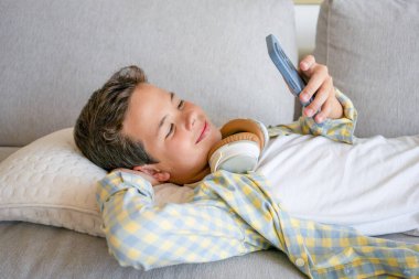 Evdeki kanepede akıllı telefon kullanan sevimli çocuk.