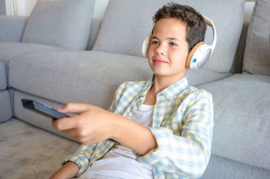 Televizyon izleyerek çok şey öğrenebilirler. Yerde otururken uzaktan kumanda kullanan bir çocuğun fotoğrafı..