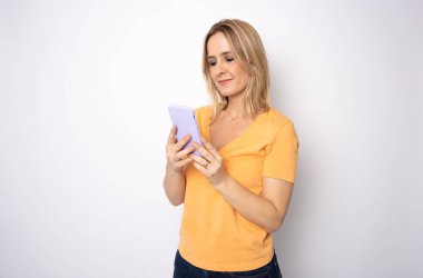 Beyaz arka planda izole edilmiş, cep telefonundan ses kaydını seçen, kulaklıklı, podcast e-kitap müzik grubu rock grubunu dinleyen, gülümseyen beyaz bir kadın.