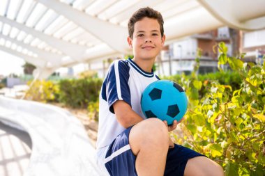 Neşeli ergen çocuk futbolu, futbol maçlarını seviyor. Futbol topu tutan çocuk, spor çocuk portresini kapat..