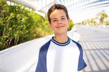 Genç mutlu çocuk yaz parkında dinleniyor. Yazın açık havada eğlenen pozitif bir genç. Çocuk esenliği kavramı.