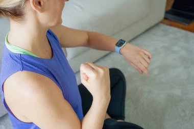 Kafkasyalı bir kadının rahat dairesinde antrenman yaparken nabzını kontrol etmesi. Spor, güç ve dayanıklılık konsepti