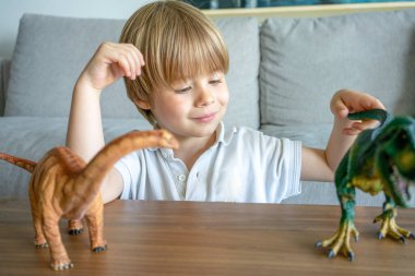 Çocuk renkli oyuncak dinozorlarla oynuyor. Çocuklar için eğitici oyuncaklar. Küçük çocuk fosil ve sürüngen öğreniyor. Çocuklar dinozor oyuncaklarıyla oynarlar. Genç çocuklar için evrim ve paleontoloji oyunu.