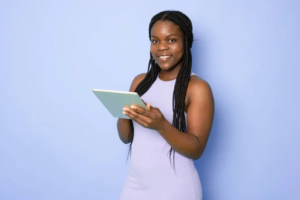 stock image Attractive young African American woman using her high-tech electronic device to help her in education isolated on light purplebackground