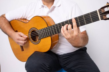 Beyaz arka planda izole edilmiş gitar çalan yetişkin bir adamın yakın çekimi.