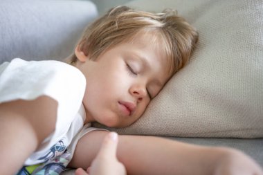Küçük çocuk evde oturma odasında kanepede uyuyor