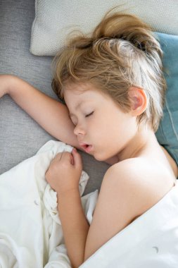 Küçük çocuk evde oturma odasında kanepede uyuyor