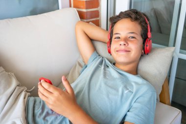 Eğlence, çocuk, teknoloji ve insan kavramı - smartphone ve müzik veya evde oyun oynarken kulaklıklar çocuk gülümseyen