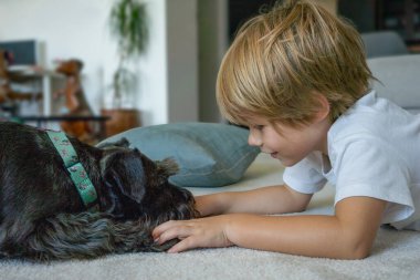 Evde köpeğiyle oynayan sevimli küçük bir çocuk.