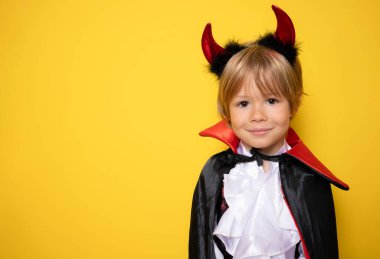 Cadılar bayramında vampir gibi giyinen küçük çocuk sarı arka planda izole edilmiş. Cadılar Bayramı konsepti
