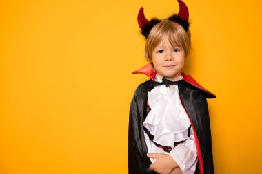 Cadılar bayramında vampir gibi giyinen küçük çocuk turuncu arka planda izole edilmiş. Cadılar Bayramı konsepti