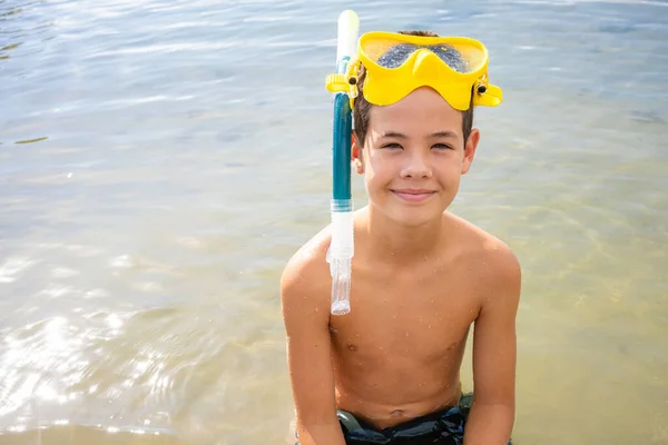 A little boy in a full face mask is snorkeling in the sea