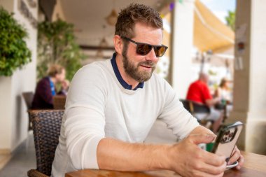 Kafe barında akıllı telefon kullanan yakışıklı adam.