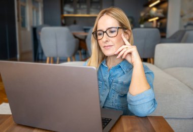 Beauitul genç kadın bilgisayarla çalışıyor konsantre ve gülümsüyor.