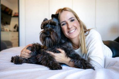 Evinde sevimli siyah Schnauzer köpeği olan genç bir kadın. Sevimli hayvan