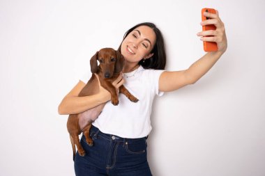 güzel kız tutan küçük bir köpek ve kendilerini telefonla otoportre yapmak
