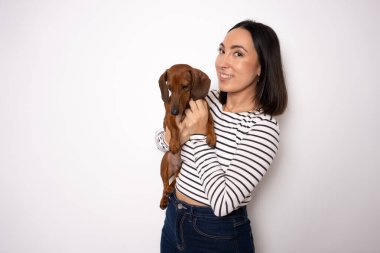 Bin yıllık sevimli bayan kucaklayan köpek resmi beyaz arka planda izole edilmiş çizgili gömlek giyer.