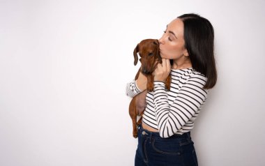 Bin yıllık sevimli bayan kucaklayan köpek resmi beyaz arka planda izole edilmiş çizgili gömlek giyer.