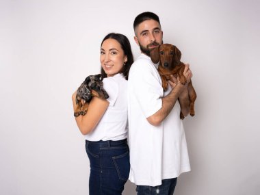 Dachshund köpeği olan yakışıklı bir çift beyaz arka planda izole edilmiş.