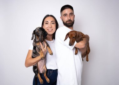 Dachshund köpeği olan yakışıklı bir çift beyaz arka planda izole edilmiş.