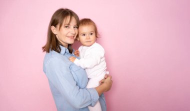 Tatmin olmuş bir anne kucağında küçük bir kız çocuğu, mutlu bir aile birlikte eğleniyor, annesinin kollarında sevimli bir çocuk, pembe arka planda izole edilmiş bir anne ve çocuk..