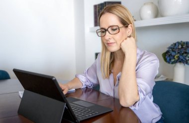 Mutlu, neşeli, güzel iş kadını imajı. Ofiste dizüstü bilgisayar kullanarak oturuyor.
