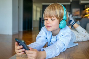 Beyaz çocuk, evde bir masanın üzerinde akıllı telefon kullanıyor.