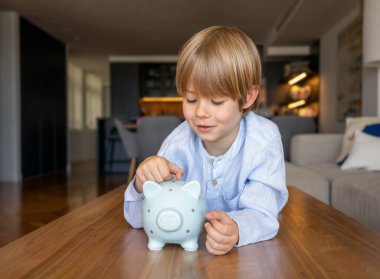 Evinde domuz kumbarası olan küçük şirin bir çocuğun portresi.