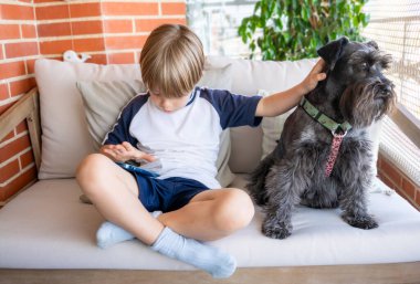 Çocuk çocuk komik mobil uygulamalar kullanıyor, evde boş vakitlerin tadını çıkarıyor, yavru köpekle birlikte oynuyor.
