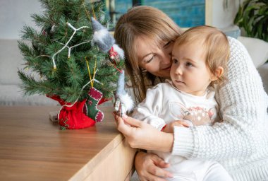 Aile, kış tatilleri ve insanların konsepti. Mutlu anne ve küçük kız evde Noel ağacı süslüyorlar.