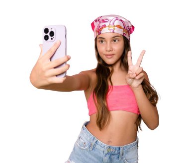 Uzun kahverengi saçlı, gülümseyen, şeffaf arkaplanda akıllı telefon tutan küçük Latin bir kızın fotoğrafı. PNG şeffaf