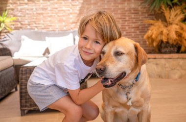 Labrador köpeğini kucaklayan gülümseyen bir çocuğun portresi..
