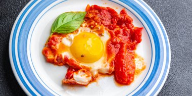 Yumurta kızartılmış domatesli Shakshuk kahvaltı yumurtaları sebze yemeği atıştırmalıkları fotokopi masasının üzerinde.